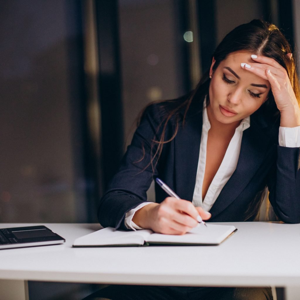 Une femme cadre travaille seule sur son ordinateur, tard le soir, dans un bureau